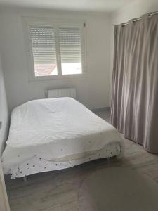 uma cama branca num quarto com uma janela em Maison en location em Le Mans