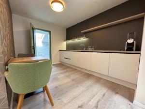 a kitchen with white cabinets and a green chair at MILIA wine & event resort in Dunajský Klátov