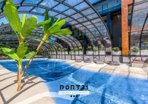 a palm tree in front of a building with a pool at Port 21 Pura Pool & Design Hotel - Adults Only in Krynica Morska