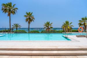 een zwembad met palmbomen en de oceaan bij El Fuerte Marbella in Marbella