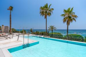 a swimming pool with palm trees and the ocean at El Fuerte Marbella in Marbella
