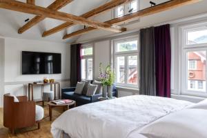 a bedroom with a bed and a couch and windows at Appenzeller Huus Löwen in Gonten