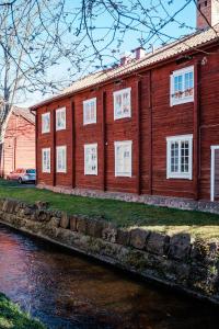 un edificio de madera con ventanas blancas junto a un río en Vandrarhemmet Färgaren en Eksjö