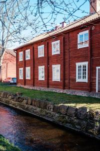 drewniany budynek z białymi oknami obok rzeki w obiekcie Vandrarhemmet Färgaren w mieście Eksjö