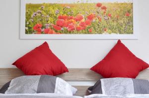 バート・ベヴェンセンにあるFerienwohnung Sperlingslustの赤い枕と壁に絵画が備わるベッドルーム1室