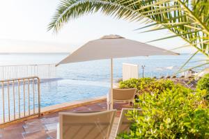 una sombrilla y sillas junto a la piscina en Hotel ROC Illetas & SPA, en Illetas