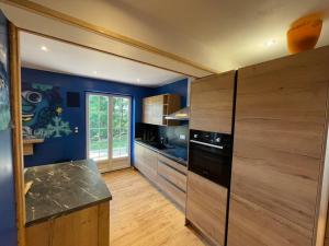 a kitchen with blue walls and a wooden counter top at La Gallerie du Domaine des lupins in Xonrupt-Longemer