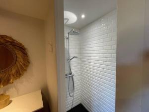 een badkamer met een douche en een witte bakstenen muur bij La Gallerie du Domaine des lupins in Xonrupt-Longemer