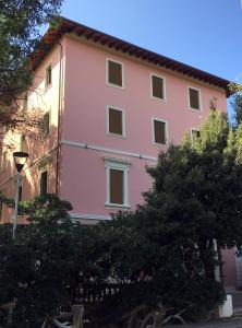 a pink building with trees in front of it at Castiglioncello Suite in Castiglioncello