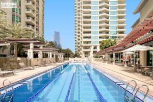 a large swimming pool with chairs and buildings at bnbmehomes - Marvellous Marina Gem nr Ain Dubai - G05 in Dubai