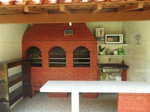 un modelo de cocina con horno de ladrillo en Vênus Apartamentos en Ilha Comprida