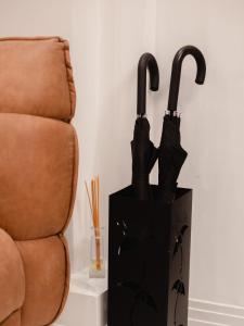 two black umbrellas in a box next to a chair at Gruner Hotel in Lviv