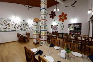 une salle à manger avec des tables et des chaises et une grande fresque murale. dans l'établissement Tathastu Kanha, à Kanha