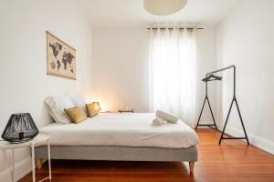 a white bedroom with a bed and a lamp at L'escapade in Schiltigheim