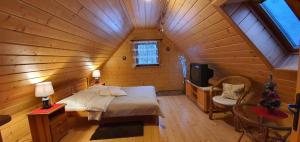 ein Schlafzimmer mit einem Bett und einem TV in einer Holzhütte in der Unterkunft Domek Górski Promyk z kominkiem in Wisła