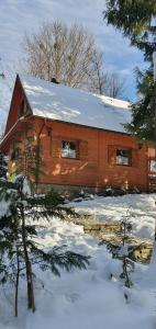 eine Holzhütte im Schnee mit Schnee darauf in der Unterkunft Domek Górski Promyk z kominkiem in Wisła