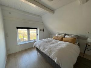 a white bedroom with a bed and a window at Løkken Family Camping & Guesthouse in Løkken