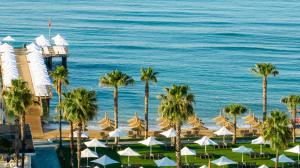 Blick auf einen Strand mit Palmen und Sonnenschirmen in der Unterkunft Voyage Sorgun Hotel in Side