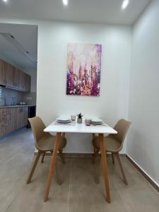 a dining room table with chairs and a painting on the wall at Georges Estates Hotel in Stoupa