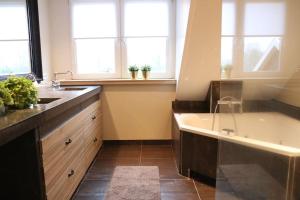 a bathroom with a tub and a sink and windows at Authentieke familieboerderij, tot 10 personen in Reutum