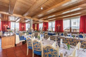 een eetkamer met tafels en stoelen en rode gordijnen bij Hotel Wenger Alpenhof in Werfenweng