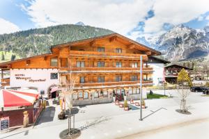 een groot houten gebouw met bergen op de achtergrond bij Hotel Wenger Alpenhof in Werfenweng