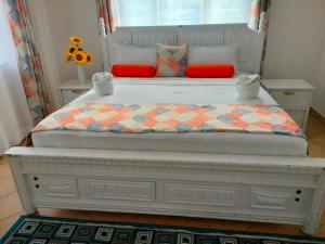 a white bed with a checkered blanket and red pillows at Sea la vie - Macheo in Ukunda