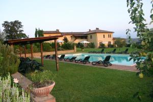 a swimming pool in a yard with chairs and a house at Agriturismo Caliano in Asciano