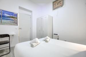 biała sypialnia z łóżkiem i ręcznikami w obiekcie Atocha Station - Apartamento de 2 dormitorios w Madrycie +6 zdjęć