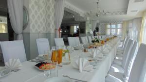 einen langen weißen Tisch mit weißen Stühlen und Teller mit Speisen in der Unterkunft Hotel Zbyszko in Stettin