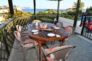 una mesa de madera y sillas en un balcón con vistas al océano en Melrose maisonette by the sea en Anavissos