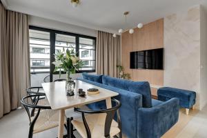 a living room with a blue couch and a table and chairs at DOKI Apartments by Blue Mandarin in Gdańsk