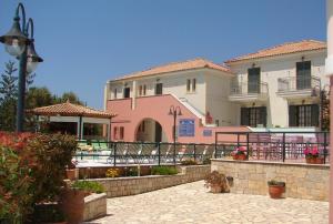 a large pink building with a patio in front of it at Georges Estates Hotel in Stoupa
