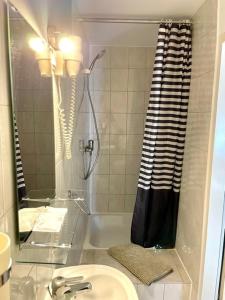 a bathroom with a shower with a sink and a mirror at Hotel Nello in Offenbach +30 photos