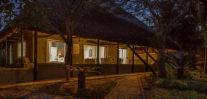 a house with a thatched roof at night at Kingfisher Creek Cottage in Hoedspruit