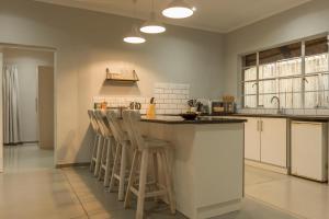 a kitchen with a counter and stools at a bar at Kingfisher Creek Cottage in Hoedspruit