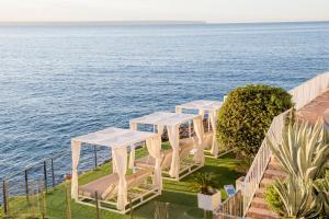 een rij witte tafels en stoelen met uitzicht op het water bij Hotel ROC Illetas & SPA in Illetas
