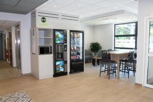 Grésy-sur-AixにあるB&B HOTEL Aix-les-Bainsの飲み物用冷蔵庫とテーブル付きのレストラン