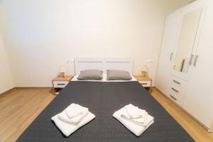 una camera da letto con un grande letto con due asciugamani bianchi di Volos Horizon Oasis Apartment #1 a Volos
