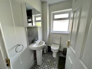 a bathroom with a sink and a toilet and a mirror at House near Swansea & Brecons! in Aberdulais