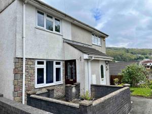 a house with a brick retaining wall in front of it at House near Swansea & Brecons! in Aberdulais