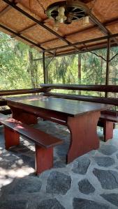 a ping pong table with two benches under a roof at Cabana Dochita 2 in Ceahlău +19 photos