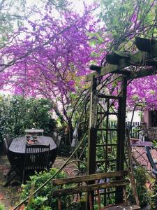 a garden with a table and a tree with purple flowers at Maison d'hôtes "les volets verts" et sa brocante in Écueillé