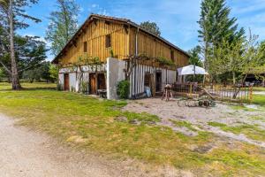 an old barn with an umbrella and a playground at Domaine les Maisons des Houssats in Trensacq