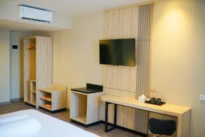 a hotel room with a bed and a television on a wall at Front One Gosyen Hotel Salatiga in Salatiga