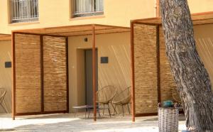 un pavillon avec des chaises et un arbre en face d'un bâtiment dans l'établissement Masseria del Carboj, à Menfi