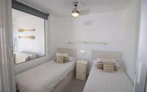 a white room with two beds and a mirror at Atico loft en primera linea EURHOSTAL Albert Villas in Alcossebre