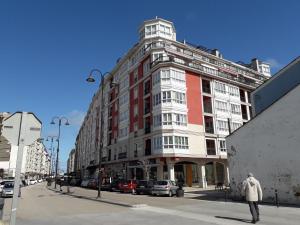 un edificio su una strada con auto parcheggiate di fronte di Atico con terraza y piscina comunitaria a Ribadeo