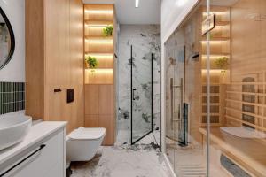 uma casa de banho com um chuveiro, um WC e um lavatório. em DOKI Apartments by Blue Mandarin em Gdansk