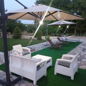 grupa krzeseł i parasol na trawniku w obiekcie Villa Il Leccio - Trulli w mieście Cisternino